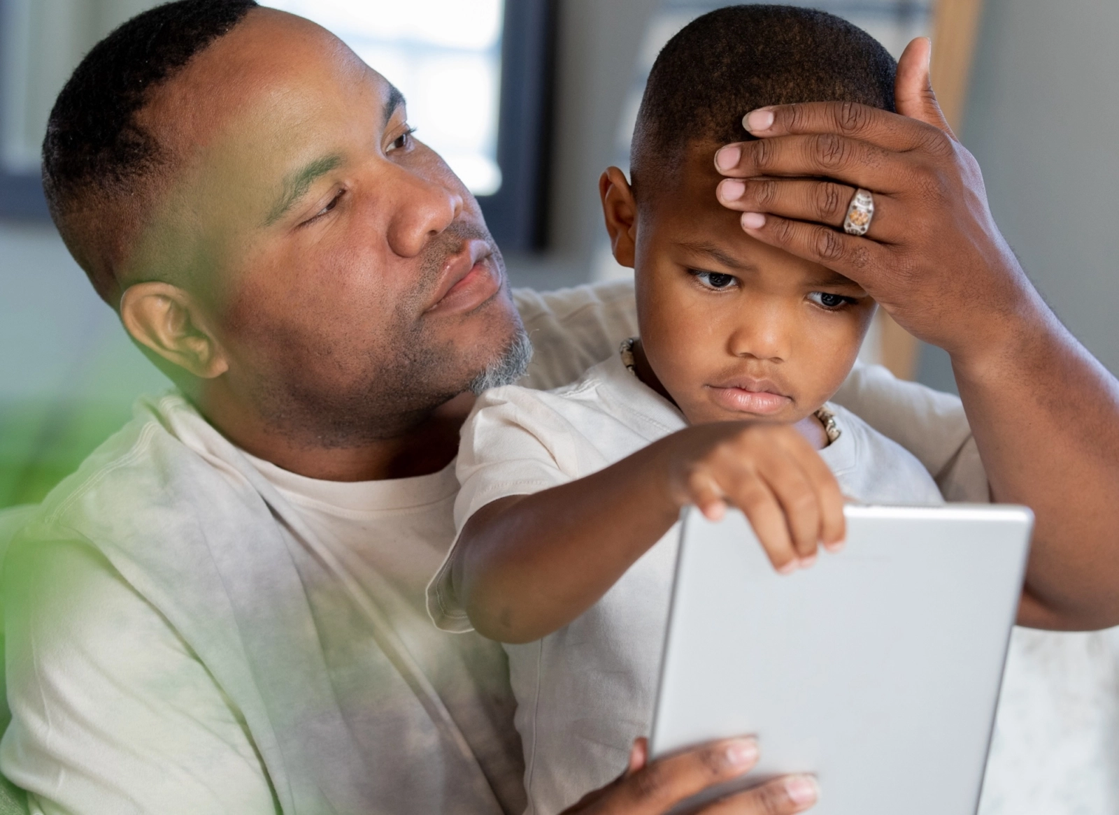 Dad taking temperature with hand on son's forehead