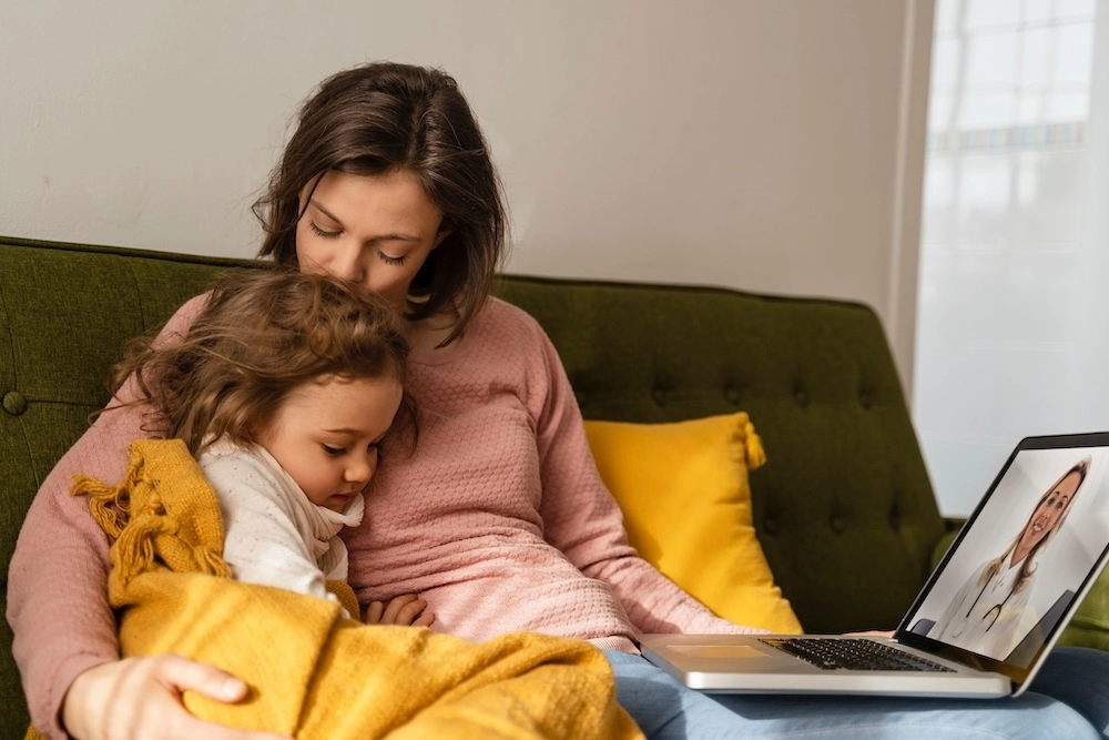 Mom and sick child on couch using Doctor On Demand.